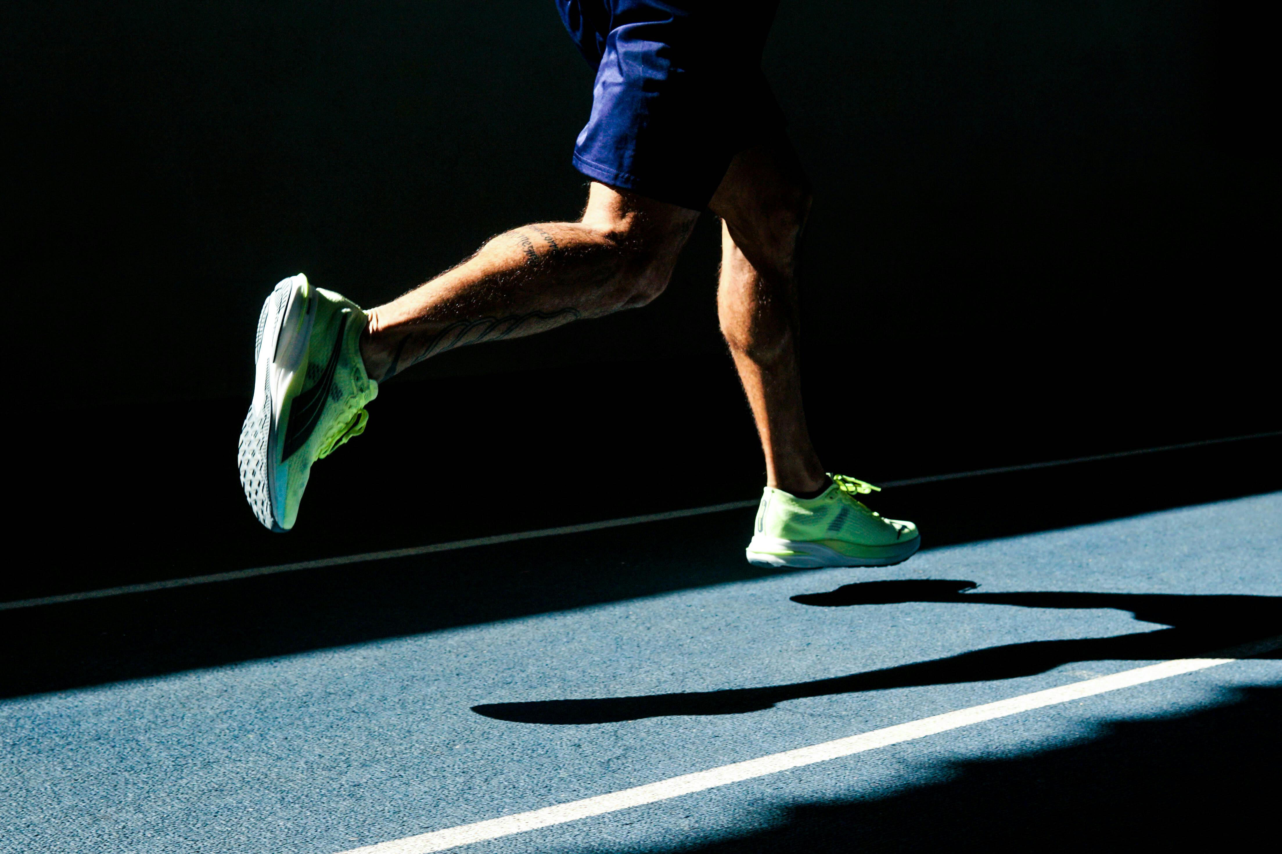 Runner's legs in motion on a track in Bragança Paulista, Brazil, casting a shadow