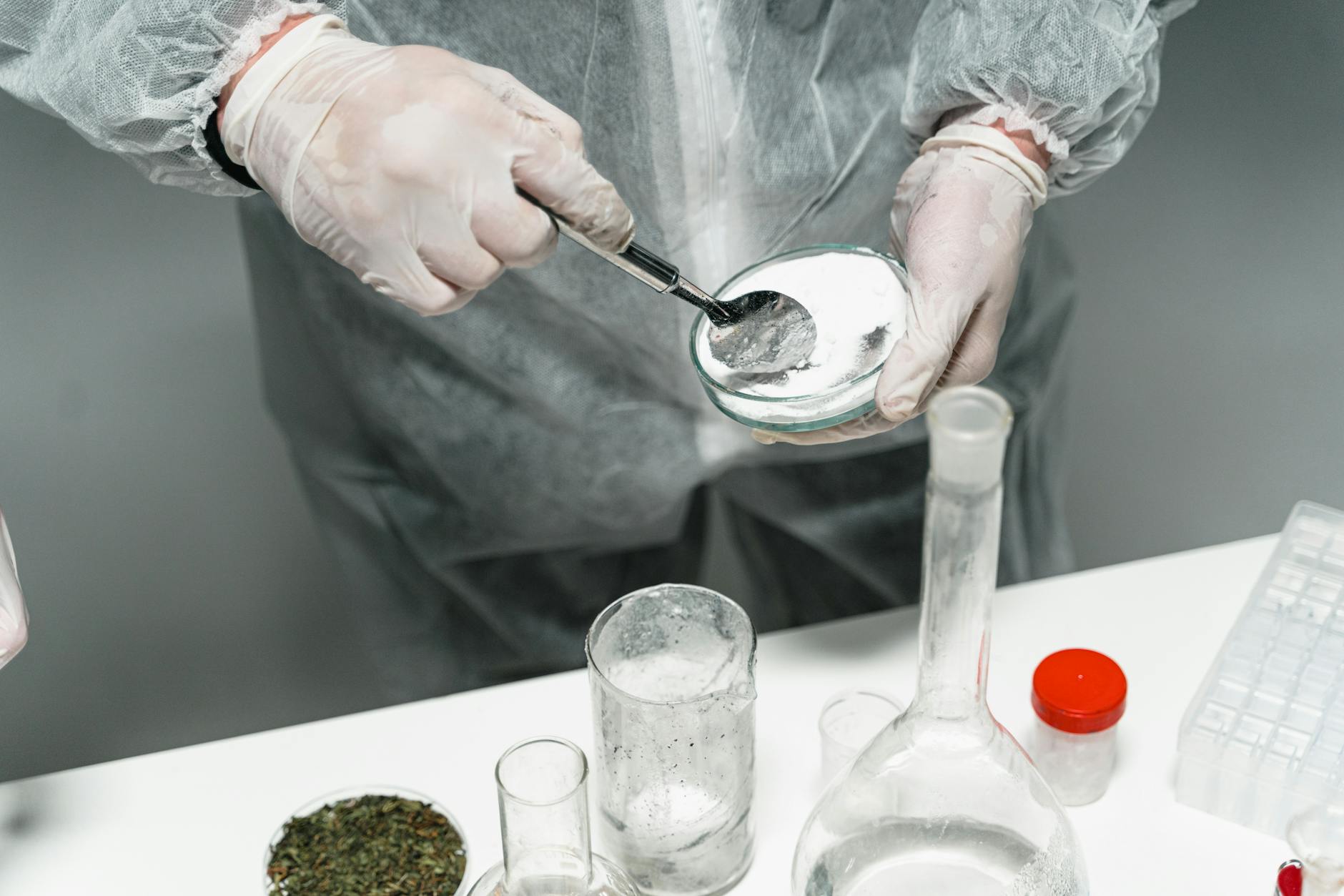 Scientist in protective gear handling powder sample in a sterile lab environment
