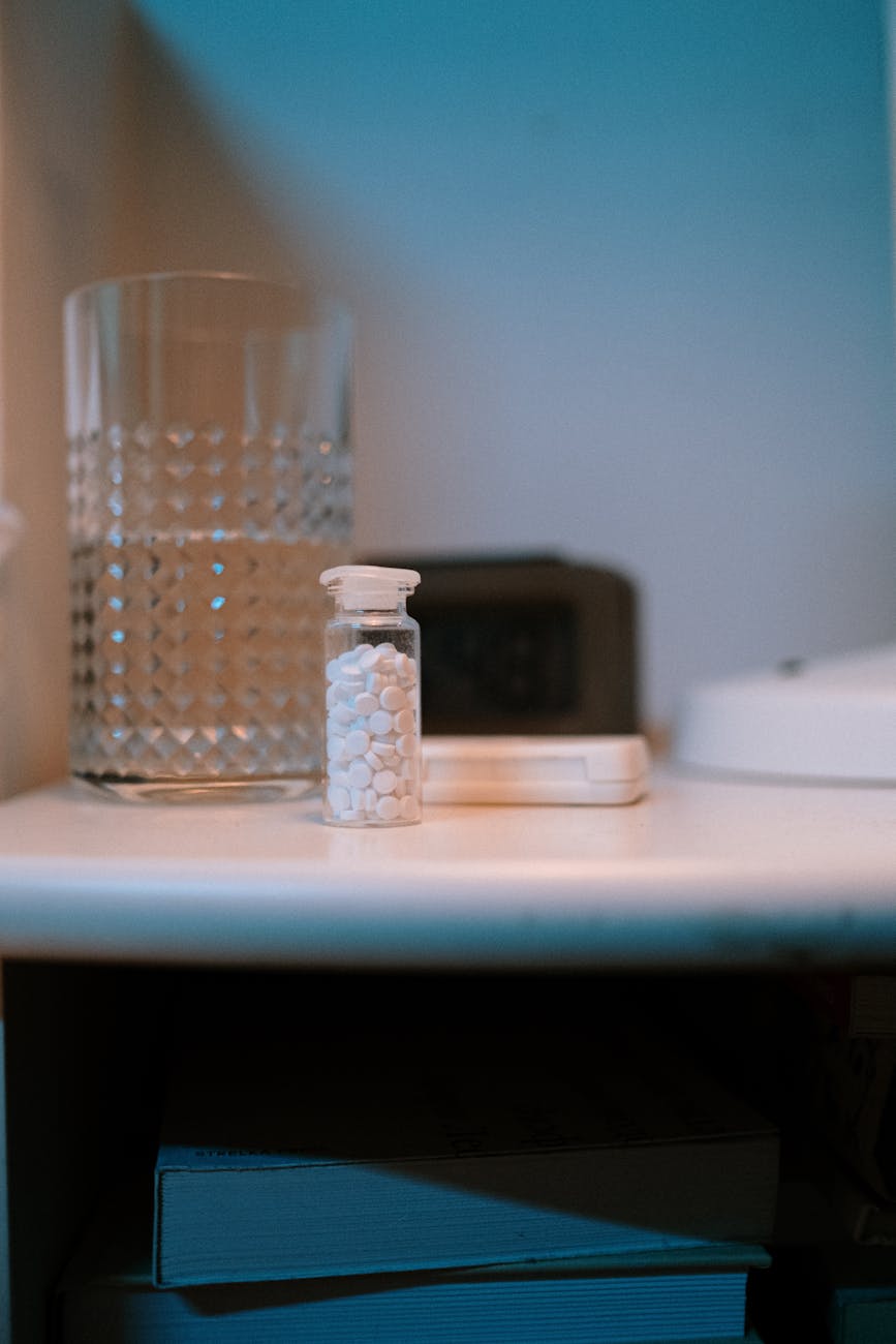 Magnesium glycinate and melatonin supplement capsules on a nightstand