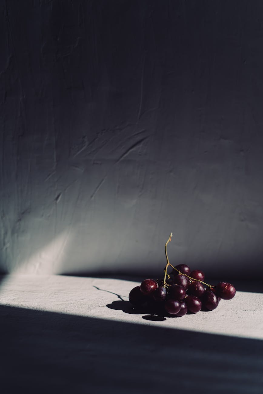 Bunch of grapes casting shadows on a white surface, illustrating the whole-fruit intervention behind the skin study.