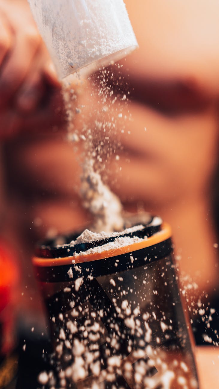 Protein powder being added to a shaker before a workout drink is mixed