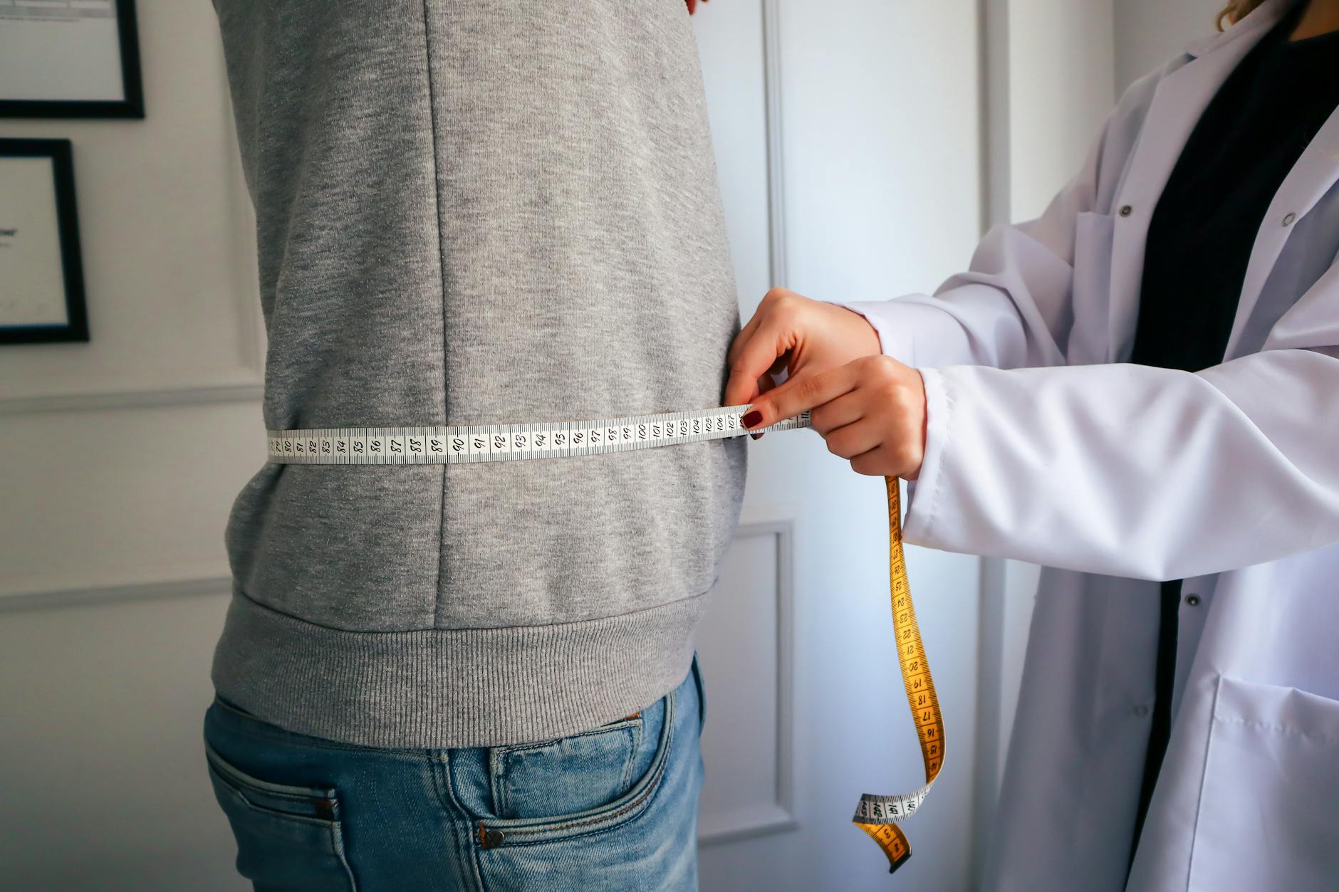 A clinician measuring a patient's waist during a body-composition assessment